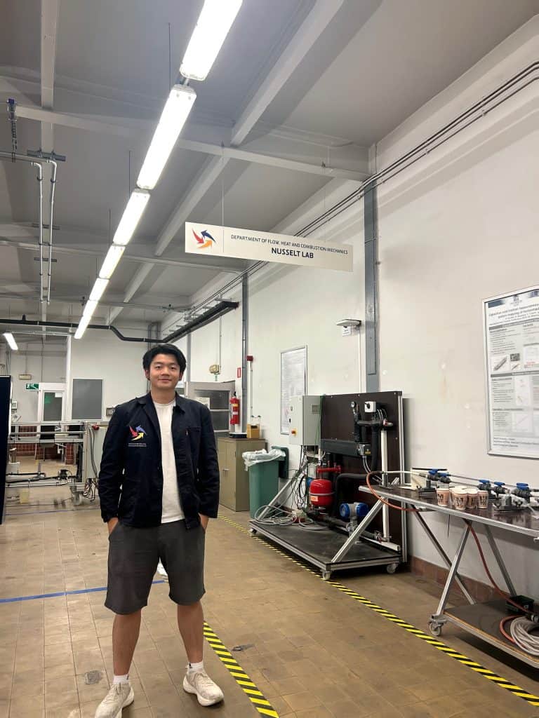 Ju Lin standing in the Nusselt Lab at Ghent University, with test equipment along the bench behind him